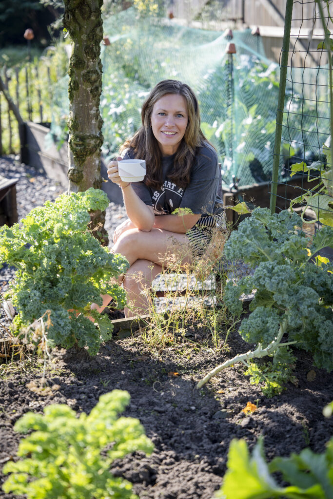 Linsey zit midden in haar moestuin met een kopje koffie